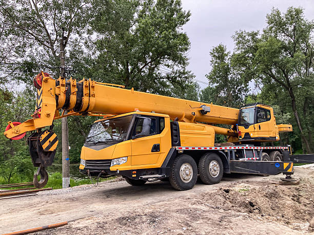 istock Yellow construction crane on dirt lot with sparse vegetation, trees in the background Flatbed trailer partly visible beneath Overcast sky diffusing light without harsh shadows Natural colors and l 2233683272