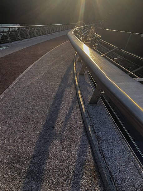 istock A modern, well-maintained curved walkway with a vibrant green surface, framed by metal railings Shadow indicates overhead structure Dawn or dusk lighting Background trees provide natural contrast 2233683301