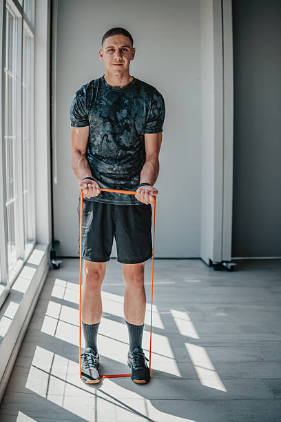 istock Fit young man performing strength training with resistance band in modern gym environment 2233688291