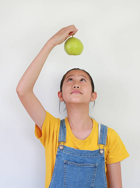 Portrait of Asian girl kid holding a fresh guava above over head isolated on white studio background.