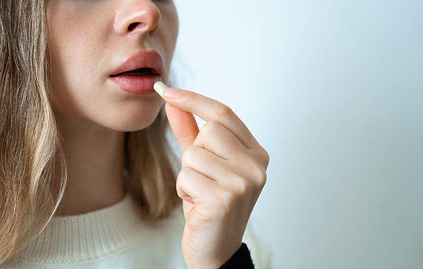 istock Woman lips close-up taking pill 2233691725