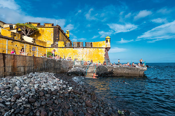 People enjoy the beach at Forte de Sao Tiago in Funchal, Madeira on a sunny day.