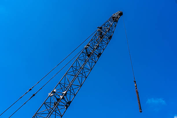 Construction crane arm extending against a vibrant blue sky, representing building and progress