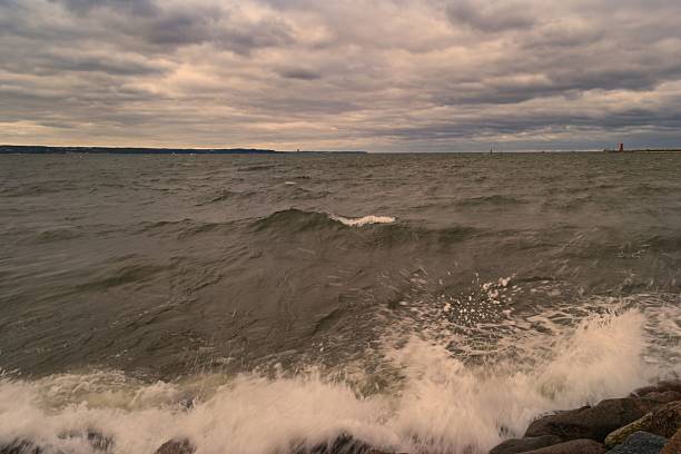 istock Cloudy sky over turbulent waters with rocky shore viewed from coastline at sunset 2233696203