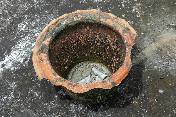 An old, empty, and broken flower pot sits on a weathered concrete roof, symbolizing garden neglect.