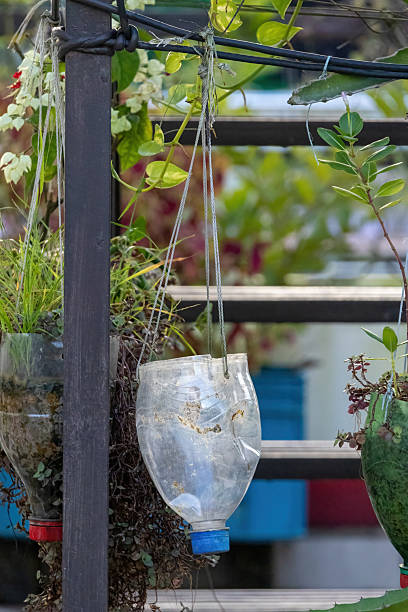 istock Close-up of an empty, hand-cut, upcycled plastic bottle serving as a hanging planter on a rooftop garden. This detail shot shows sustainable DIY craftsmanship for gardening and home decor. 2233697295