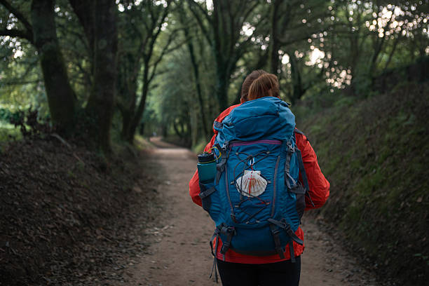 A young woman walking along a rural path in a peaceful wine region, backpacking.