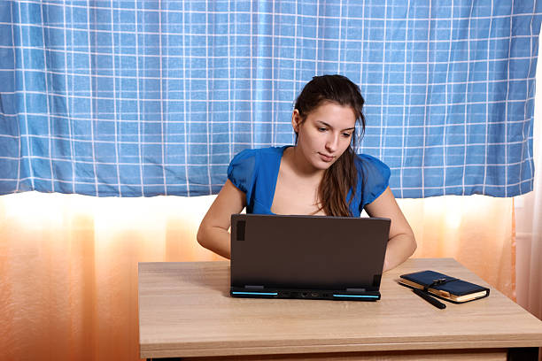 A female student studies at home on a laptop.