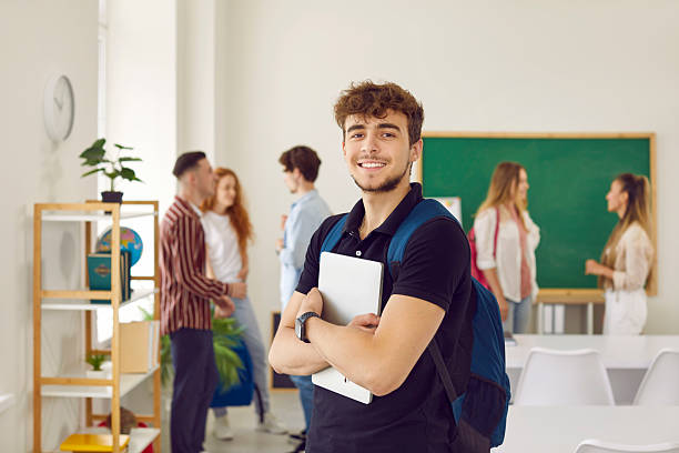 istock Portrait of student with backpack and tablet computer against background of class with his classmates 2233704132