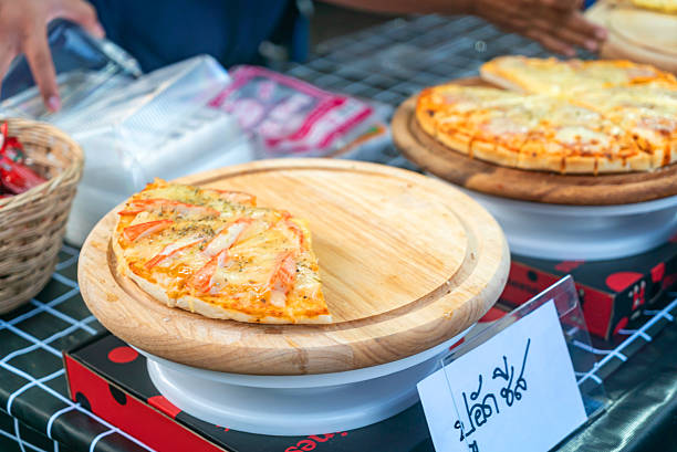 A freshly baked slice of pizza on a wooden board, showcasing a delicious blend of toppings. Perfect for a tasty snack or casual meal at outdoor markets.