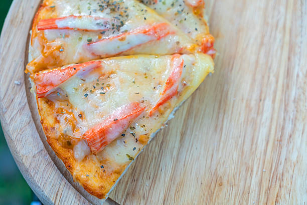 This image showcases a fresh slice of pizza topped with seafood and melted cheese, beautifully presented on a wooden board, perfect for food enthusiasts.