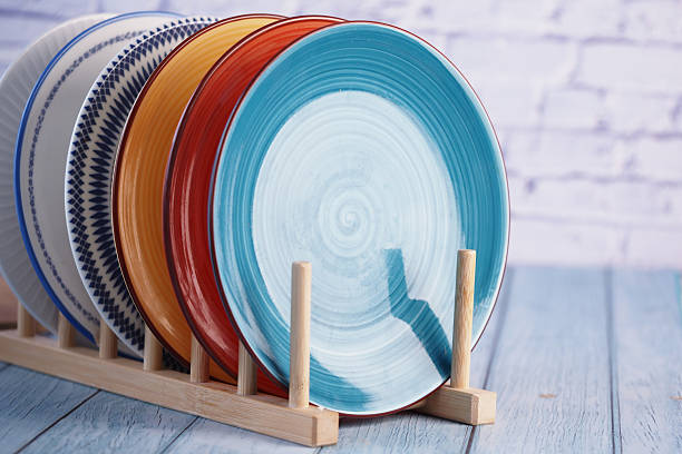 istock Colorful plates arranged in a wooden rack on a light blue background 2233707994