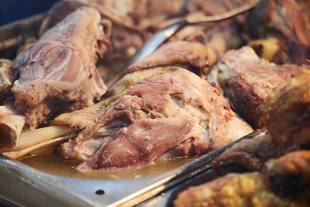 Tender meat is displayed in a tray at a bustling food stall.