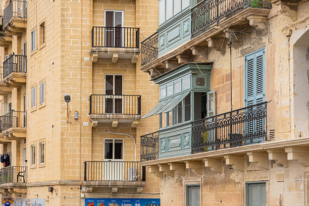 alletta, Malta – June 26, 2021: Traditional Maltese wooden balconies painted in pastel colors, alongside stone facades and wrought iron railings, Valletta, Malta.