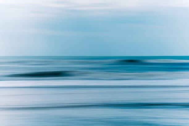 istock Gentle waves roll toward the shore under a cloudy blue sky. Abstract seascape 2233711412