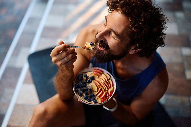 istock Athletic man eating oatmeal with fresh fruit during home workout. 2233714746