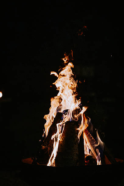 istock Close-up of a roaring fire pit at night with visible flames and burning logs, creating a warm, glowing ambiance in the dark. 2233715854