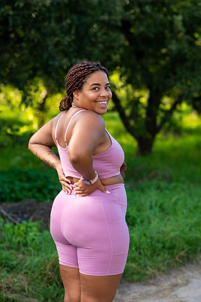 istock Curvy woman posing with hand on back and joyful smile over shoulder 2233716175