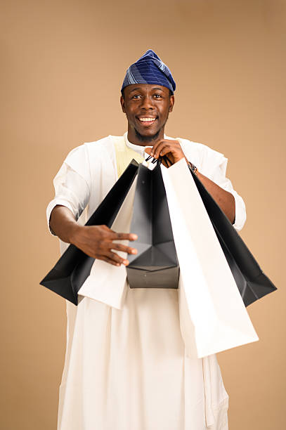 istock Smiling man in agbada holding shopping bags 2233744072