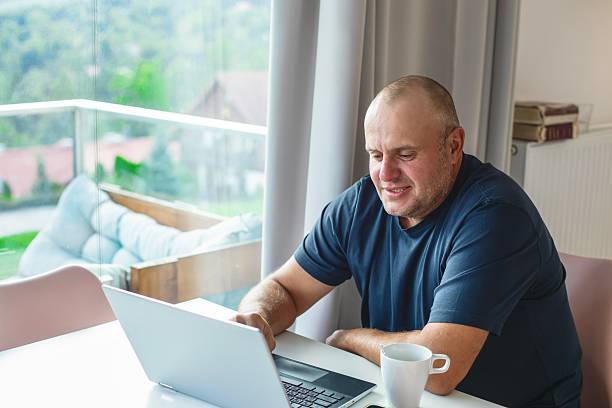 istock Middle-aged man drinking morning coffee and communicating via laptop. 2233745241