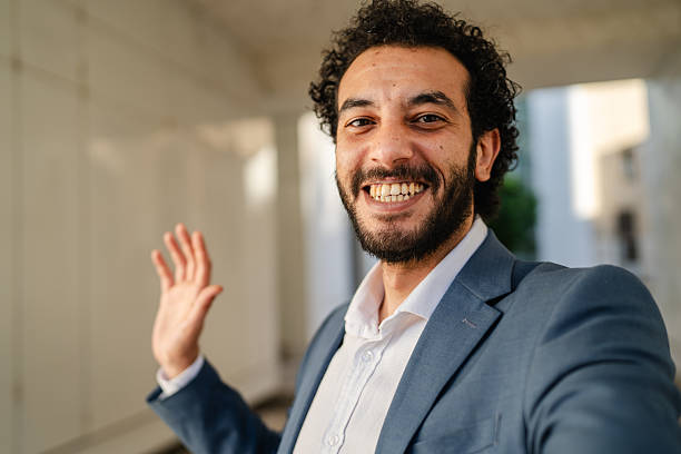istock Smiling businessman waving and gesturing during video call in hallway 2233745329