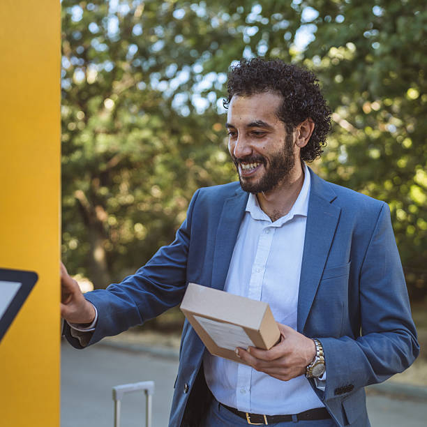 Entrepreneur is opening an automated locker to retrieve a package, enjoying the convenience and efficiency of modern delivery systems in a bustling urban environment