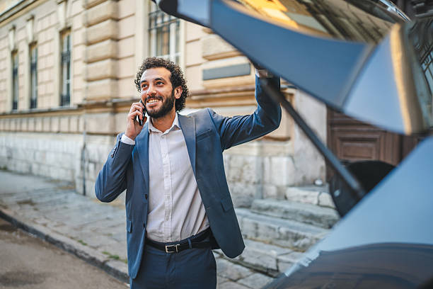 istock Businessman opening car trunk while talking on phone 2233745689