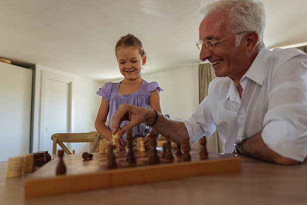 istock Grandfather teaching granddaughter playing chess at home 2233746387