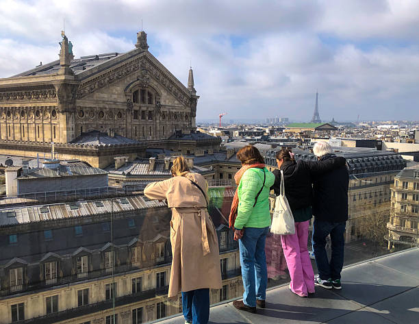 Paris, France - March 28, 2025: Tourists looking out over the Opera Garnier, with the Eiffel Tower in the distance.