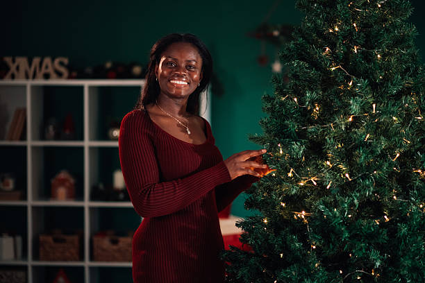 istock Young woman decorating christmas tree at home 2233749985