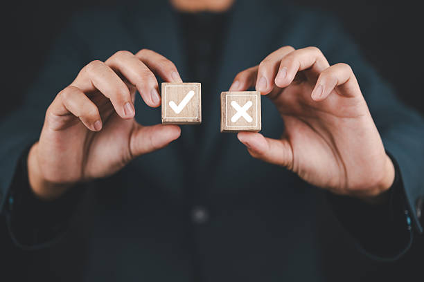 istock Businessman is thinking and making choices between right and wrong symbols. Decide to vote concept. Yes or No decisions, business options in difficult situations. True False, crisis decision making. 2233751931