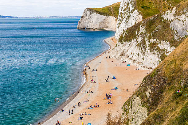 High angle view of crowded Durdle Door beach with tourists and white cliffs, Dorset