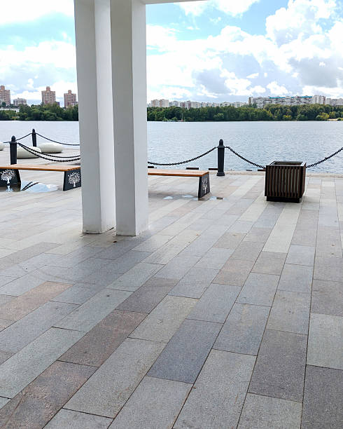 istock Waterfront with white columns and benches river view and cloudy sky 2233759953