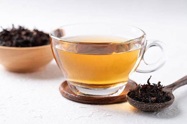 istock Black tea in cup glass with dried tea leaves on white background 2233760511