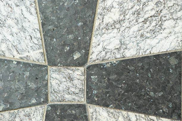 Mosaic depicting a stunning arrangement of dark and light-shaded granite tiles, offering a beautiful contrast. The textured and durable stonework reflects exceptional craftsmanship and adds a classic architectural appeal.