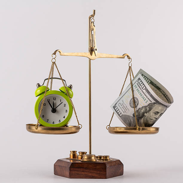 istock A US$100 bill and an alarm clock on a scale 2233776077
