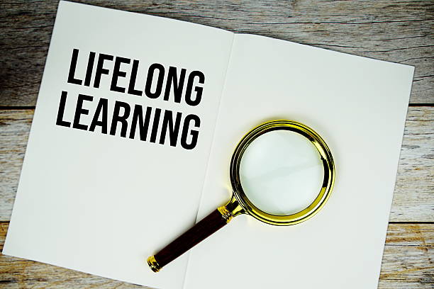 istock Lifelong Learning text message written on paper note with magnifying glass top view on wooden background 2233777501