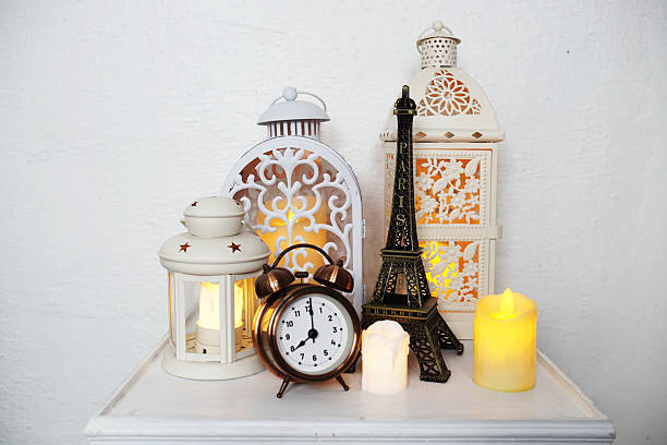 istock Home decoration accessories Eiffel statue, alarm clock, white lantern and LED candle light on wooden table 2233778220