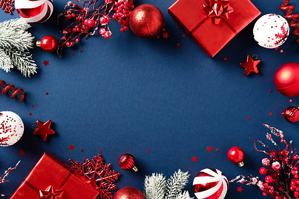 istock Christmas frame with red gift boxes, baubles, snowflakes, berries, and frosted pine branches on dark blue background. 2233784711