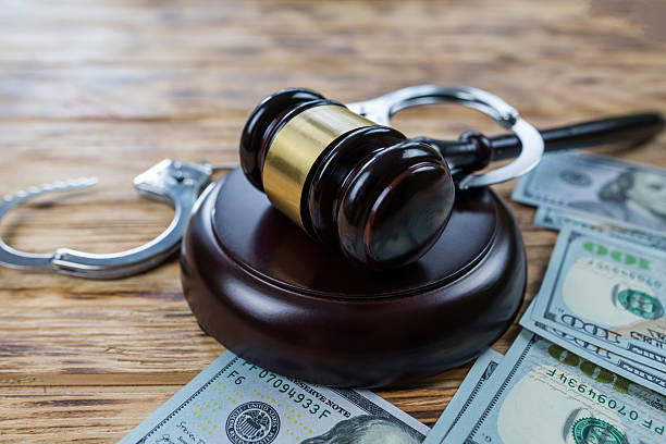 istock judge's gavel, dollars and handcuffs on a wooden table. 2233786542