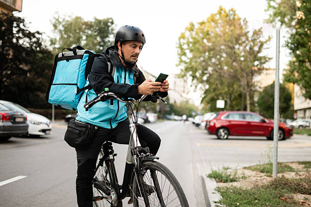 istock Deliveryman using smartphone and riding bicycle in city 2233786967