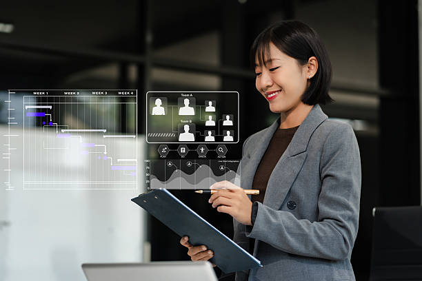 istock woman hand Project manager working and update tasks and Gantt chart scheduling virtual diagram with smart phone and laptop in office 2233794668