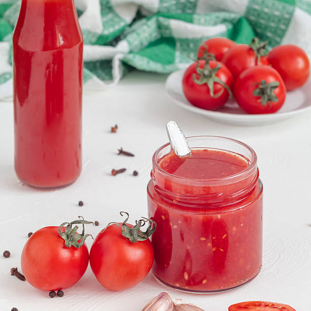 istock Fresh tomato sauce in a glass bottle, red cherry tomatoes on a white background. Side view. 2233798631