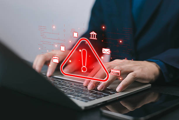 istock Businessman using laptop with red warning alert hologram, symbolizing cybersecurity threat, data breach, online fraud, malware attack, phishing, and digital security risk in technology. 2233800376