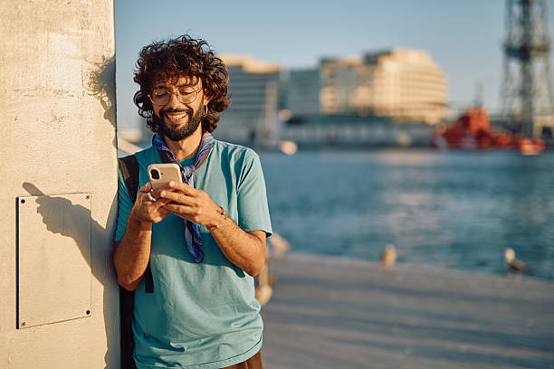 istock Young tourist using phone in Barcelona harbor at sunset 2233801380