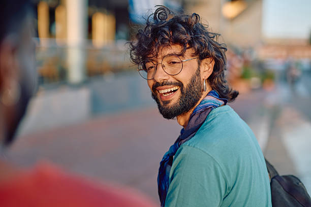 Young man laughing while talking with a friend outdoors