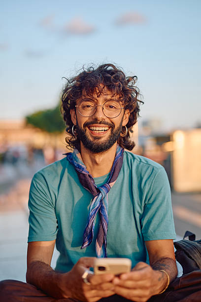 istock Stylish man using smartphone and smiling at camera outdoors 2233801476