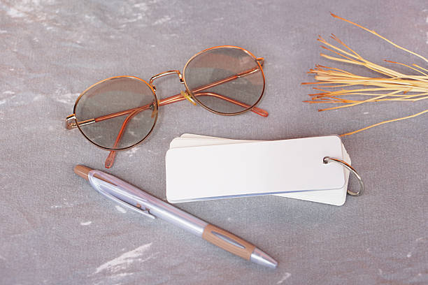 Blank spiral notepad with empty pages placed on gray fabric background, decorated with pen, eyeglasses, dried branches. Minimal stationery setup, perfect for mockup, design, or creative presentation