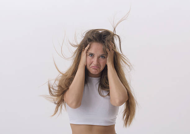 Frustrated stressed young woman with head in hands and messy hair, she has a hair problem, copy space