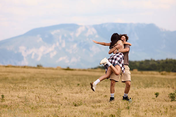 Happy couple having fun while spinning during spring day in a meadow. Copy space.